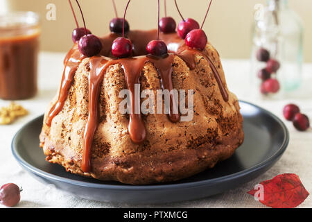 Apple pie with nuts, decorated with salted caramel and small red apples. Rustic style. Stock Photo
