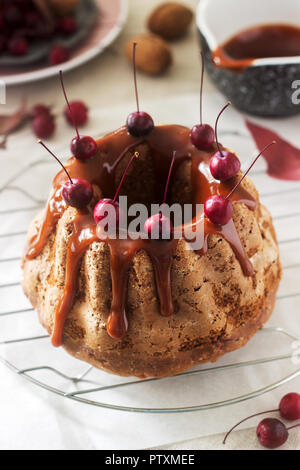 Apple pie with nuts, decorated with salted caramel and small red apples. Rustic style. Stock Photo
