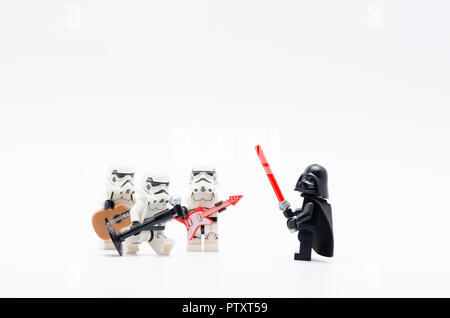 lego darth vader watching storm troopers holding mic with one of them holding a guitar. Stock Photo