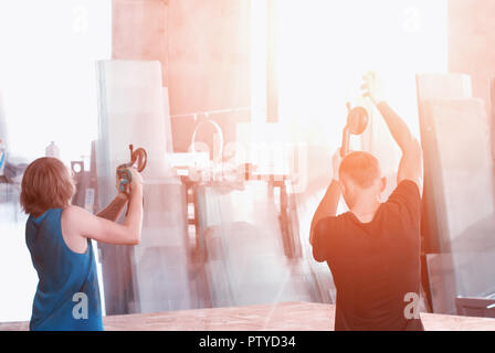 Production of pvc windows, workers on suction cups transfer glass for the production of double-glazed windows, workman Stock Photo