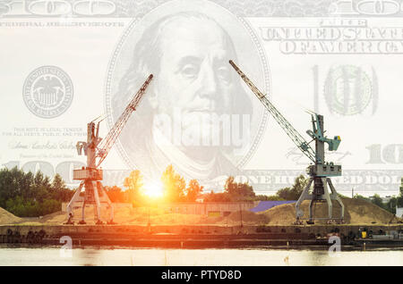 Two port cranes unload river sand from the barge, against the background of the sky a hundred dollars, the sunset, dollars Stock Photo