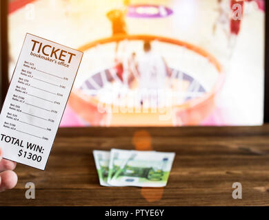 Bookmaker ticket and euro money on the background of a TV on which basketball is shown, bookmaker Stock Photo
