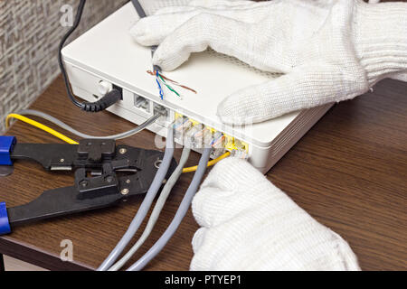 A man connects a network cable to the modem, a close-up Stock Photo