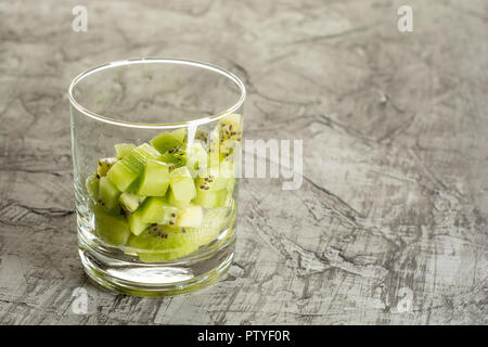 Healthy fresh kiwi slices in glass on concrete background. Stock Photo