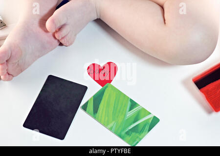 Baby legs and credit cards on white background, heart Stock Photo