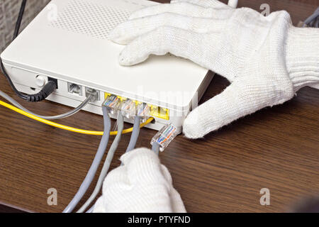 A man connects a network cable to the modem, a close-up Stock Photo