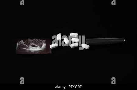 Uzi shot, pills and test tube on a black background, abortion, close-up Stock Photo