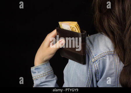 Girl holding a purse with money (euro) back view, close-up, black background Stock Photo