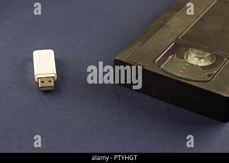 A white flash drive on a blue background and a video cassette Stock Photo