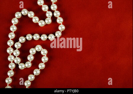 White pearl necklace on reddish brown leather background. Stock Photo