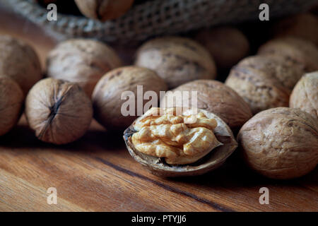 Whole walnuts (in shell) in burlap sack on wooden background Stock Photo