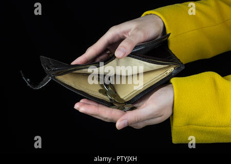 Female hands hold a purse from which poured coins, a black background Stock Photo