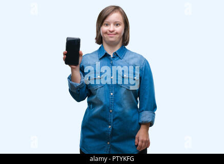 Young adult woman with down syndrome showing smartphone screen over isolated background with a happy face standing and smiling with a confident smile  Stock Photo