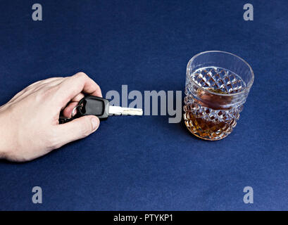 A man's hand holds car keys and alcohol, close-up Stock Photo