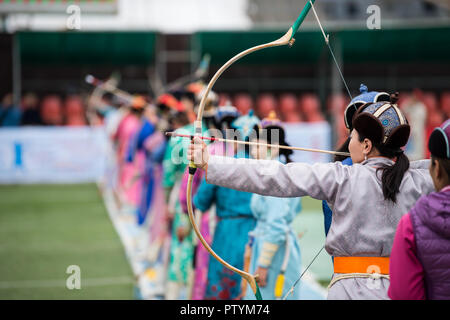 Naadam festival Mongolia archery, Mongolian women in traditional Mongolian dress shooting arrows with Mongol bow and arrow, colorful traditional costu Stock Photo