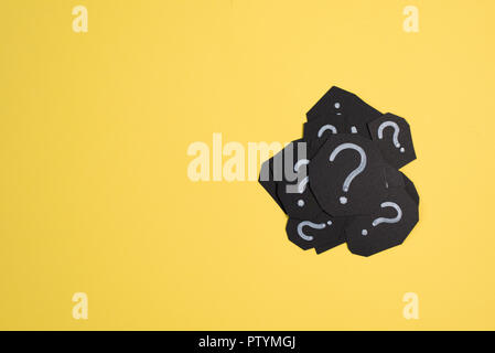 heap of black paper card with QUESTION MARK on bright yellow background. Concept of FAQ, Q&A, Problems and Questions Stock Photo