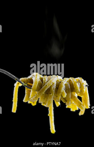 Closeup of spaghetti with pesto sauce rolled on a fork. Isolated over black background. Stock Photo