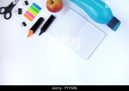 Study stuff. Education background. Stationery. Aspects of education. Stickers, bottle, markers, scissors, clips, apple and notebook on the table. Stock Photo