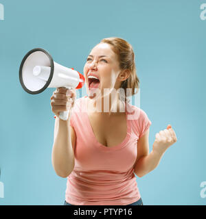 Woman making announcement with megaphone at blue studio Stock Photo