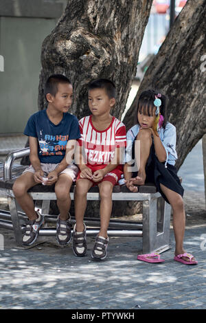 Three young friends sitting on a bench. Thailand Southeast Asia Stock Photo