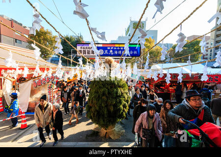 Japanese new year, shogatsu. Ikuta Shinto Shrine in Kobe. Crowds of people walking along narrow road towards the large kadomatsu decoration and torri Stock Photo