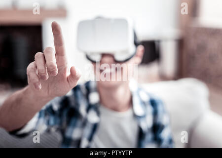 Cheerful man touching transparent screen while using virtual reality glasses Stock Photo