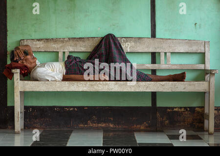Yangon, Myanmar - October 2: Unidentified burmese man having rest on the white bench. Stock Photo