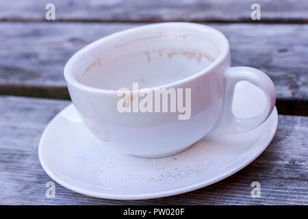 A used empty coffee cup and saucer on a wooden table, closeup, United Kingdom Stock Photo