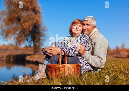 https://l450v.alamy.com/450v/pw02bb/senior-couple-having-picnic-by-autumn-lake-happy-man-and-woman-enjoying-nature-and-hugging-peaceful-landscape-pw02bb.jpg