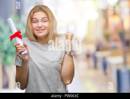 Young caucasian woman holding degree over isolated background screaming proud and celebrating victory and success very excited, cheering emotion Stock Photo