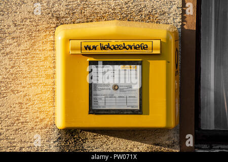 Standard yellow letterbox of German Postal Service, with (ironic) lettering 'only love letters' Stock Photo