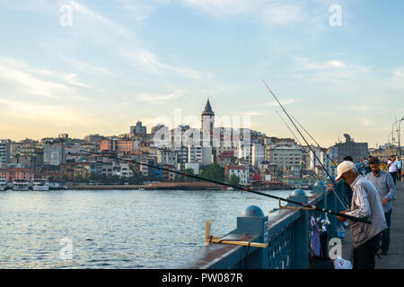 Galata bridge with fishermen fishing at sunset with Galata tower and Karakoy district in background, Istanbul, Turkey Stock Photo