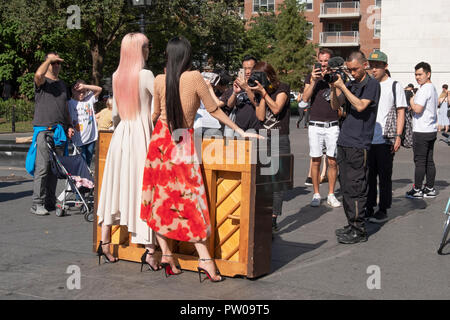 Two beautiful slender Japanese models, their photographers, entourage & onlookers in Washington Square Park in Greenwich Village, New York City. Stock Photo