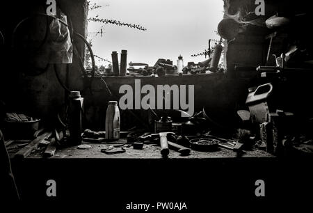 Old workbench, with old tools, in disarray, lit by window,various containers on bench, cluttered Stock Photo