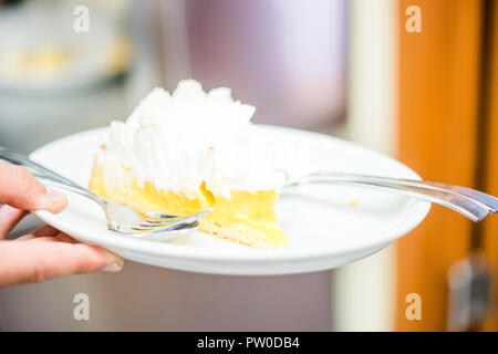 Lemon meringue pie on white plate hold by man Stock Photo