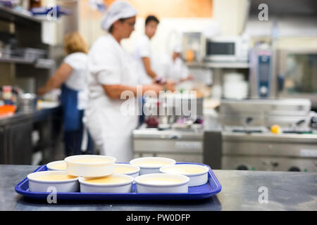 Many bowls with creme Brulee and staff working in the kitchen as background Stock Photo