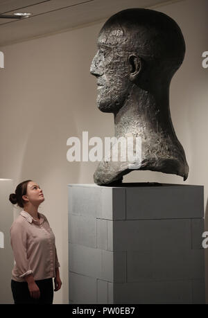 A visitor looks at a Tribute Head on display at the Elisabeth Frink Humans and Other Animals exhibition preview at the Sainsbury Centre for Visual Arts in Norwich, Norfolk. PRESS ASSOCIATION Photo. Picture date: Thursday October 11, 2018. The exhibition will provide new perspectives and examine her radical and bohemian beginnings in 1950s London, reappraising one of the most important British sculptors of the twentieth century. Photo credit should read: Chris Radburn/PA Wire Stock Photo