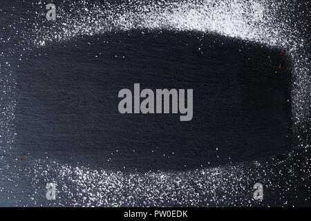 Frame made of powdered sugar on a black kitchen slate plate. Abstract background. Top view. Stock Photo