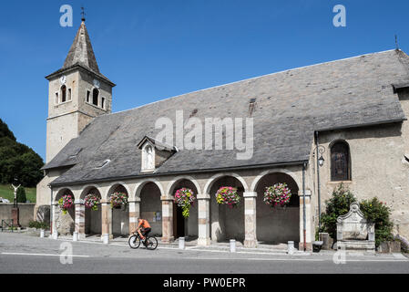 Cyclist riding in front of the church of Notre-Dame-de-l'Assomption in Sainte-Marie-de-Campan, Hautes-Pyrénées, France Stock Photo