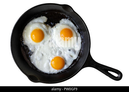 Three fried eggs in cast iron frying pan isolated on white from above. Stock Photo