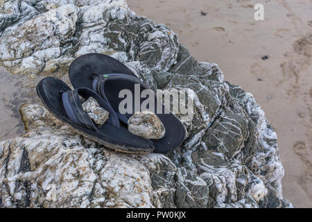 Beach sandals (weighted down with small stones as indicator the shoes are not 'Lost' or left by mistake). Stock Photo