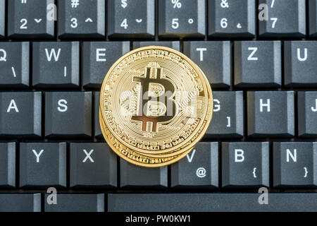 Conceptual of cryptocurrency with golden bitcoins on a black keyboard, top view. Stock Photo