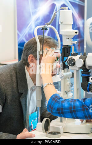 Patient eye doctor checkup patient eyes with apparatus. health care, medicine, people, eyesight and technology concept - man checks his vision on the  Stock Photo