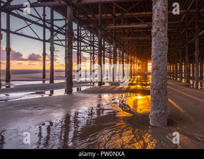 Sunset under Blackpool's famous South Pier, just outside Blackpool Pleasure Beach on the Fylde Coast in the North West of England Stock Photo