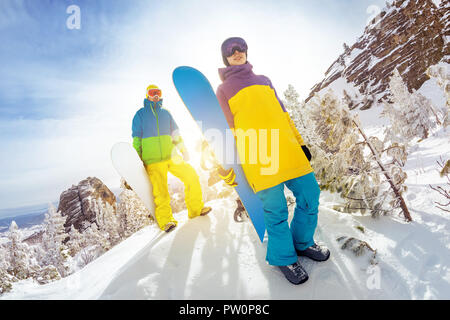 Two snowboarders male and female stands at offpiste ski slope with snowboards in hands Stock Photo