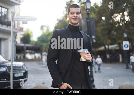 Laughing young man holding coffee to go, early morning, walking in the city Stock Photo