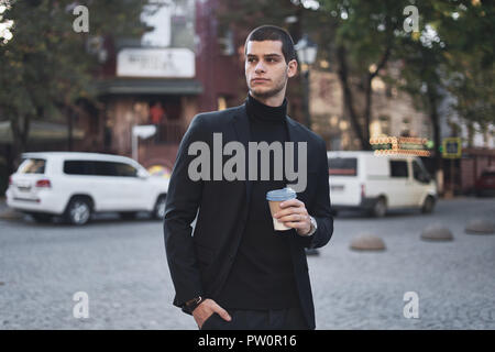 Confident young man holding coffee to go, early morning, walking in the city Stock Photo