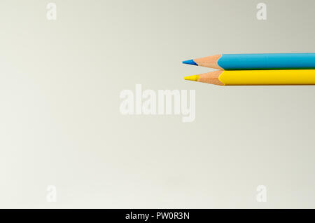 Two pencils of yellow and blue colour on white sheet background. Symbolical flag of Ukraine. Stock Photo
