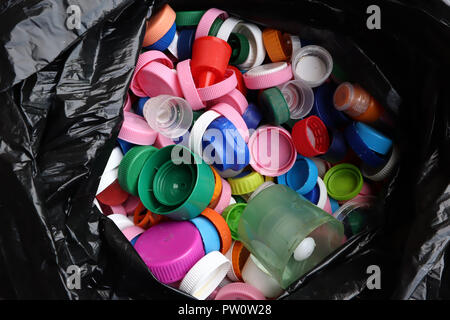 group of multicolored bottle caps in black plastic bag, ready for recycling top view Stock Photo