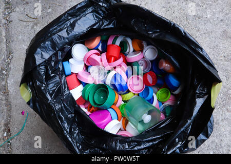 group of multicolored bottle caps in black plastic bag, ready for recycling top view Stock Photo